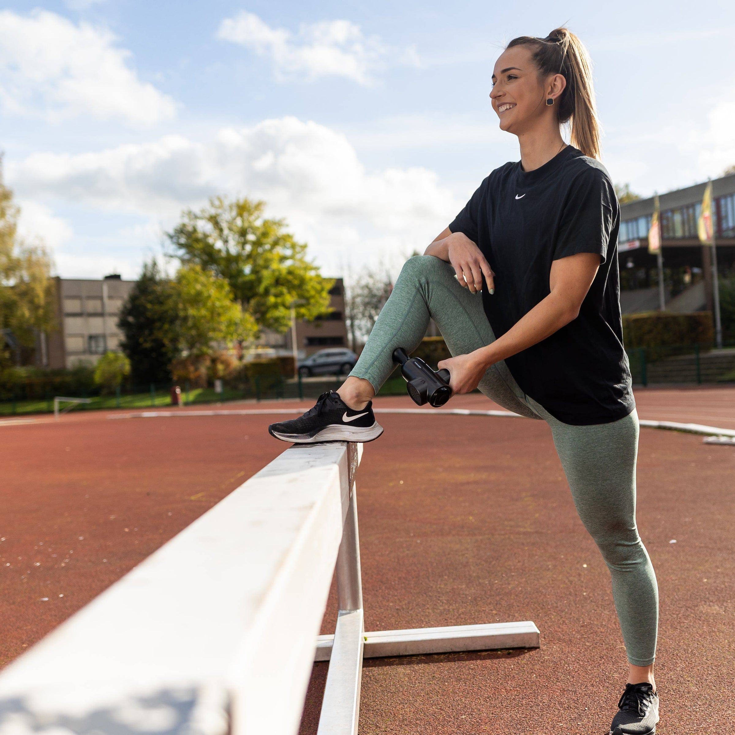 Sportieve vrouw gebruikt massage gun op haar kuiten